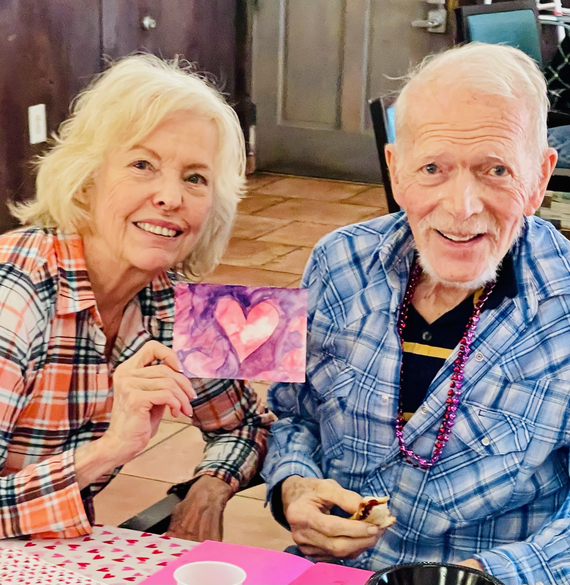 Dementia communication tips: two people seated together holding colorful heart artwork